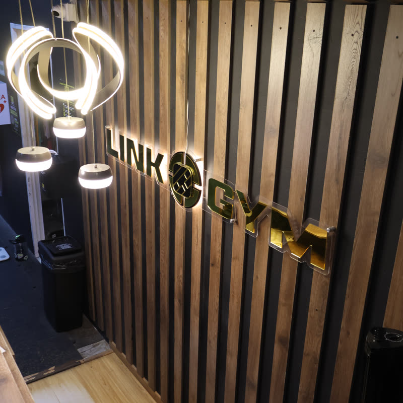 Letrero Link Gym en relieve sobre pared de listones de madera