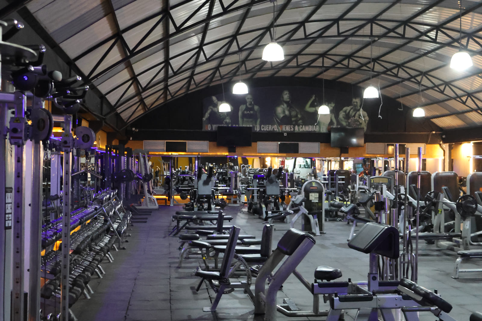 Salón principal de LinkGym Kennedy, con techo de arcos metálicos y filas de máquinas